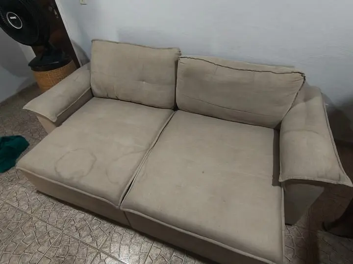 Sofá bege de dois lugares com marcas de sujeira e manchas circulares no assento, antes da limpeza